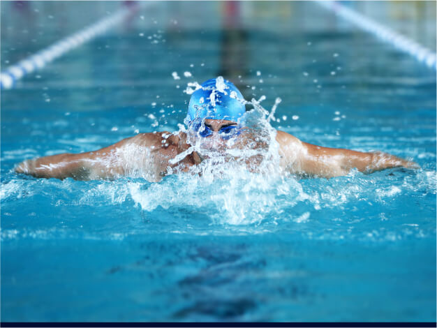 Swimmer in butterfly style – showcasing the grace and power of butterfly stroke in swimming. Experience optimal performance and comfort with AQTIVAQUA's premium swim gear designed for competitive and recreational swimmers